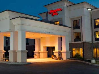 This image shows the entrance of a Hampton Inn hotel at night, with its illuminated canopy.